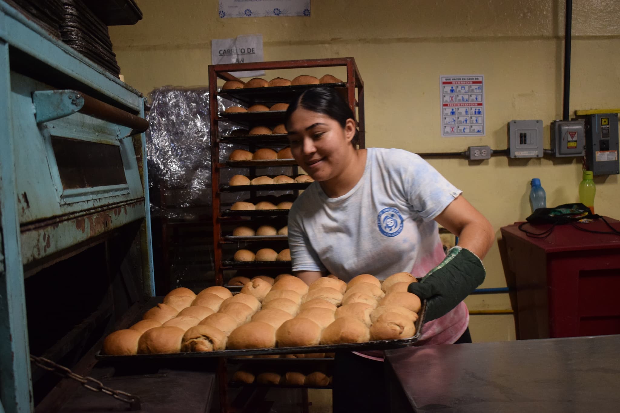 Mädchen holt Blech mit Brötchen aus dem Ofen