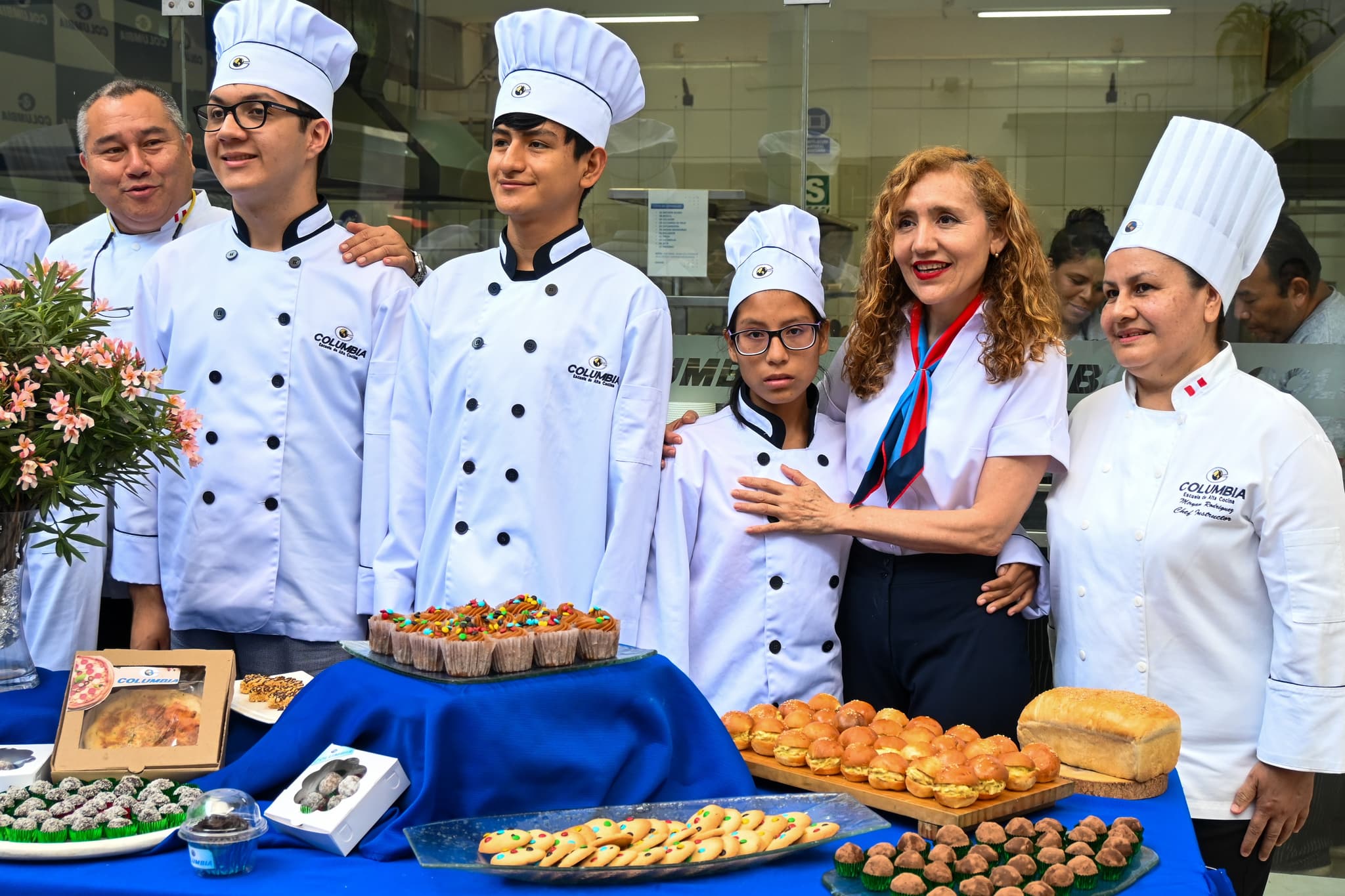 Absolventen der Bäcker-Ausbildung, die nebeneinander stehen und alle ihre Bäckerei-Outfits tragen.