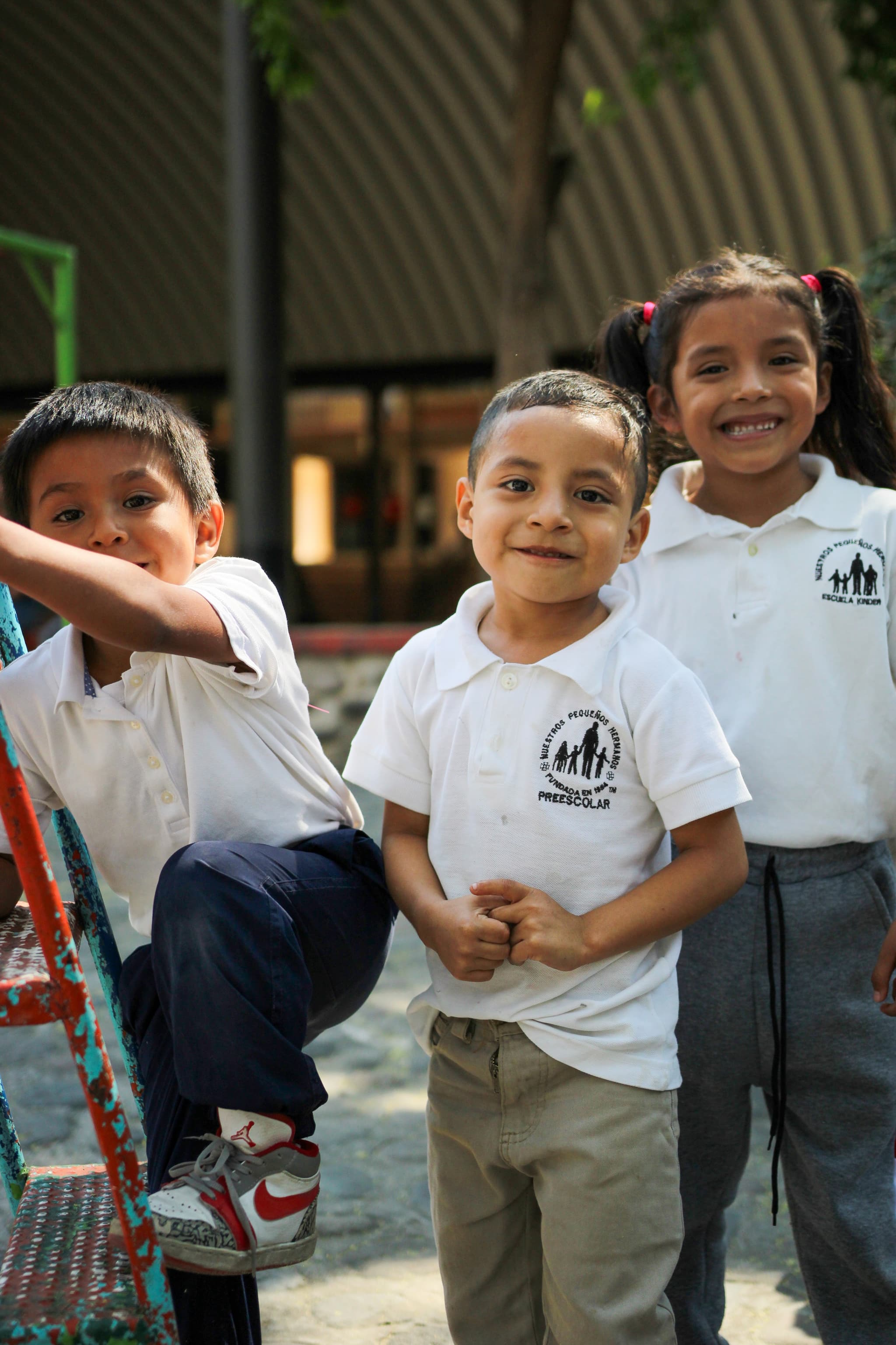 Drei Jungs aus dem Kinderdorf mit weißen nph-Shirts.