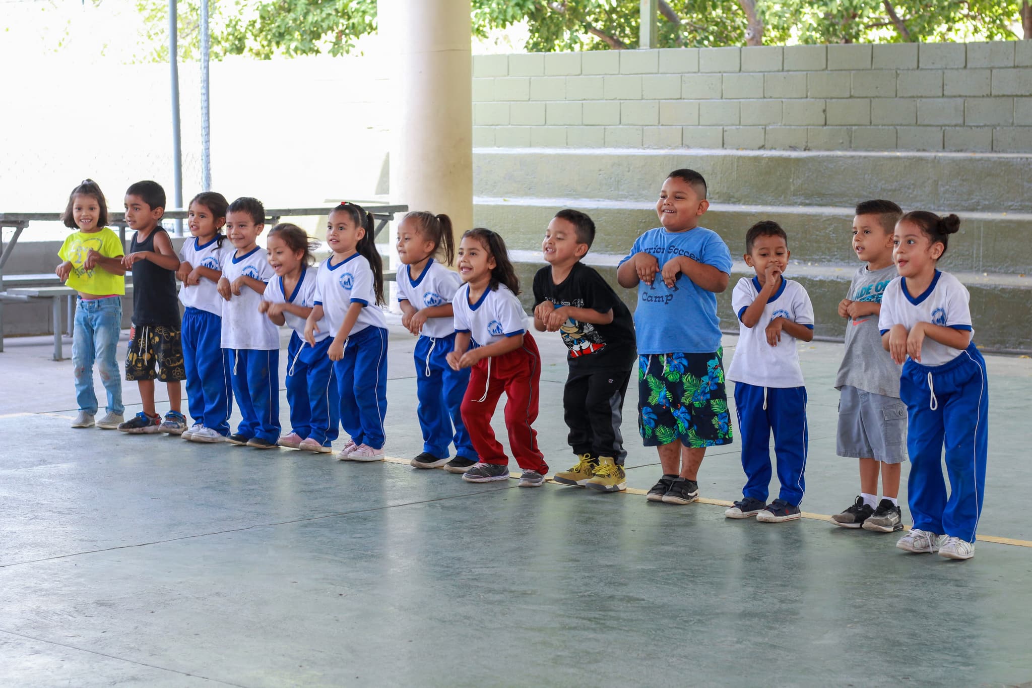 Eine Gruppe von kleinen Kindern steht nebeneinander, bereit mit Sportübungen zu starten