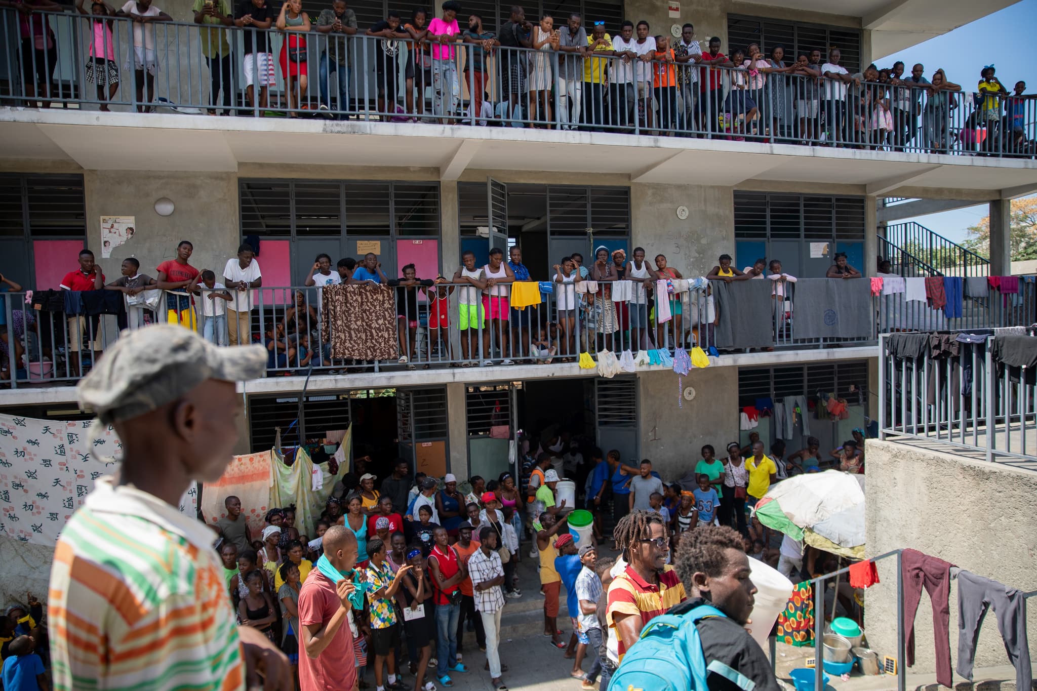 Menschen aus Haiti die vor und innerhalb einer Notunterkunft auf den Balkonen stehen.