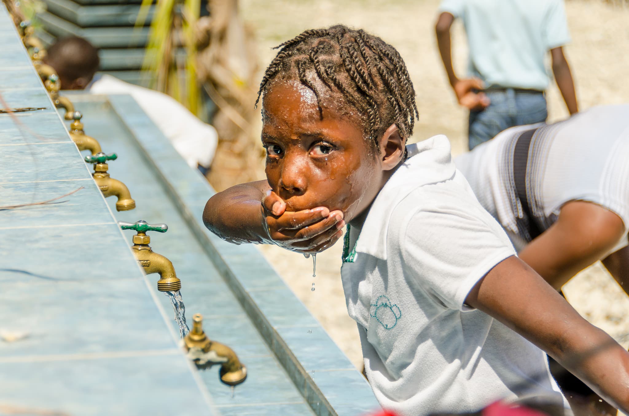 Junge in Haiti versorgt sich mit Wasser aus Wasserhahn